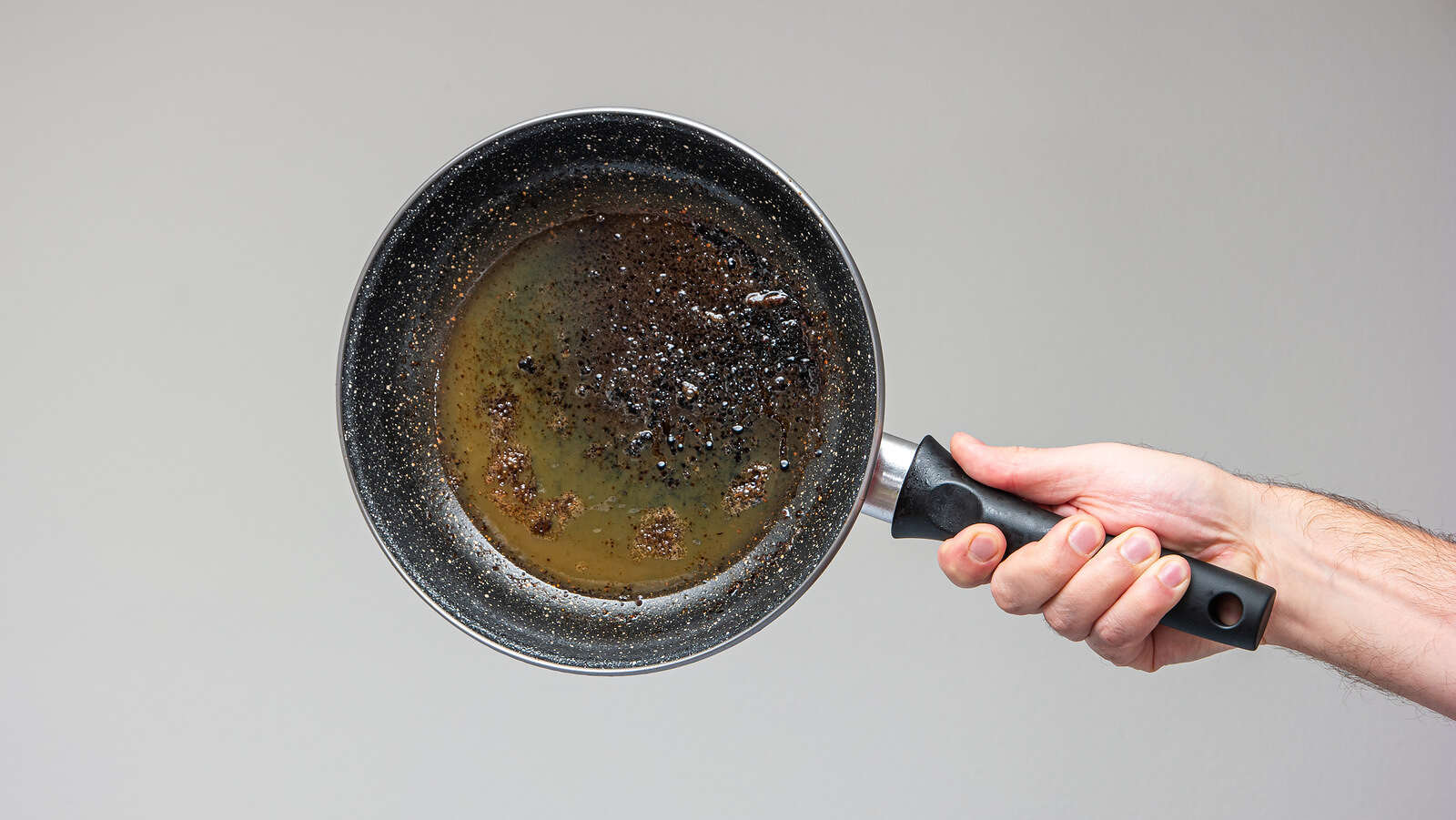 Caucasian,Male,Hand,Holding,An,Old,Frying,Pan,Stained,With طاسة قلي (tastingtable)